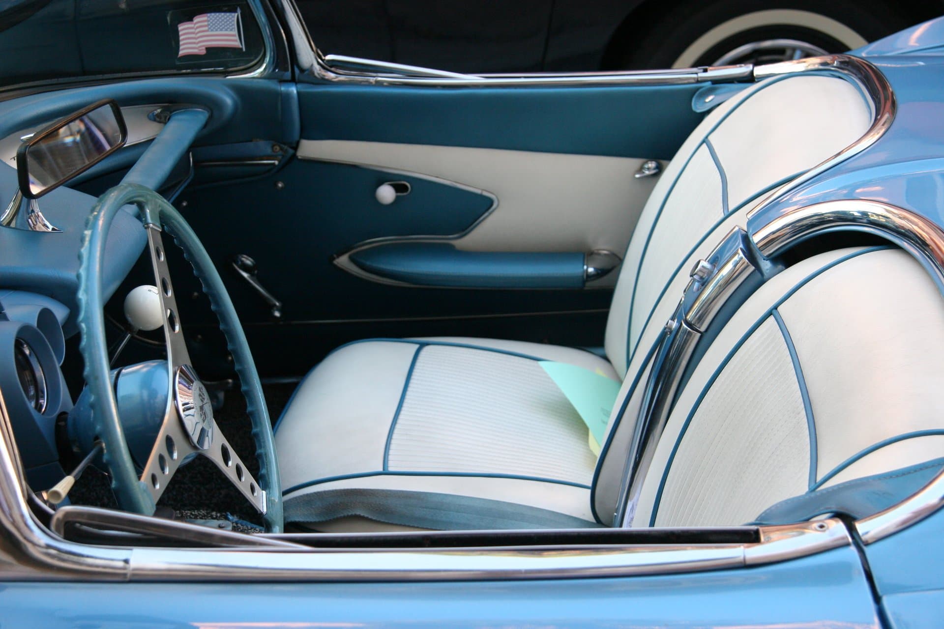 Restored teal and white leather interior of a classic convertible with chrome trim